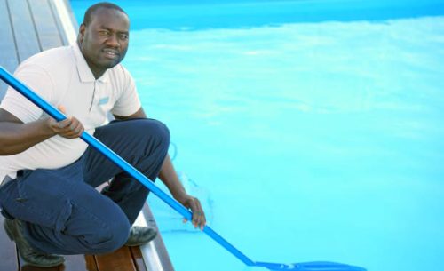 Pool cleaner during his work. Hotel staff worker cleaning the pool.